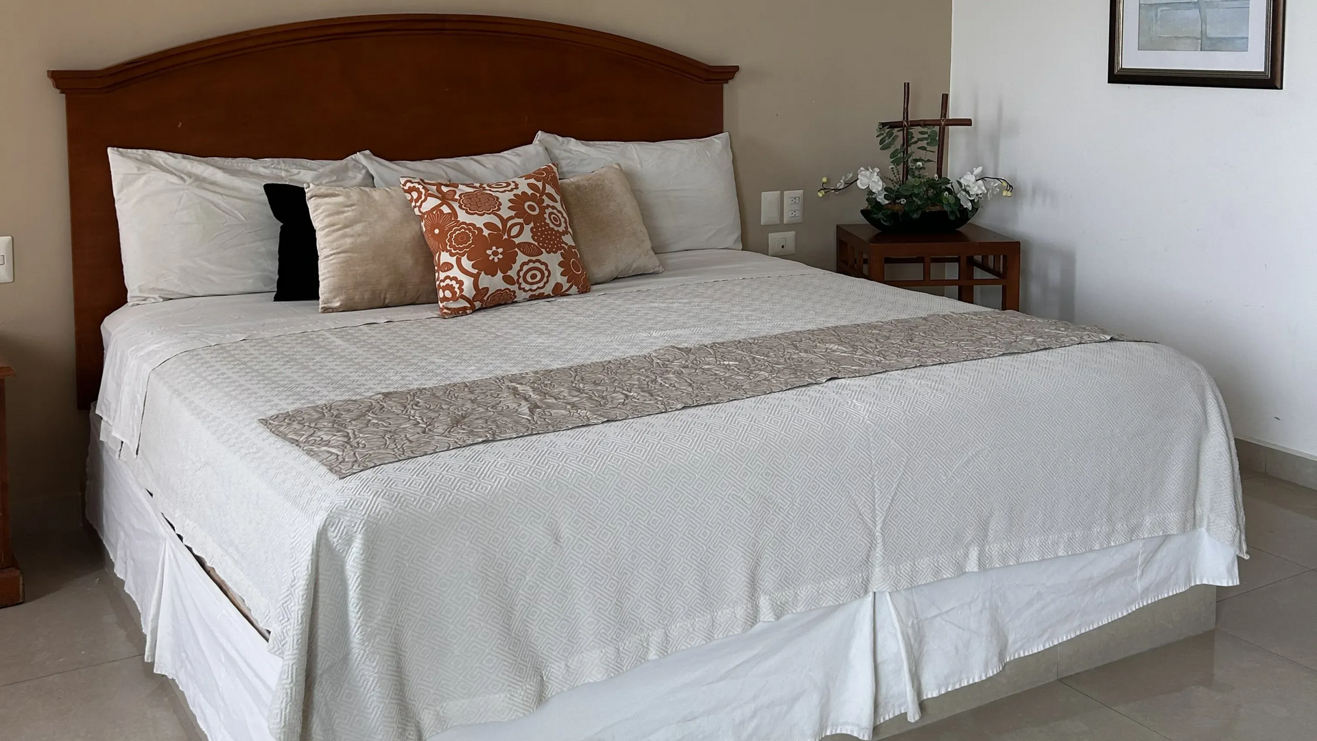 Una cama bien hecha con ropa de cama blanca, cojines decorativos.