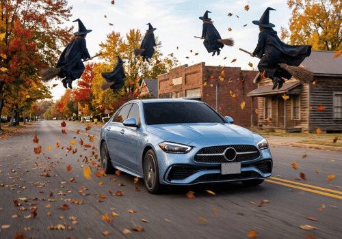 Mercedes-Benz sedan driving along an autumn street surrounded by flying witches on broomsticks