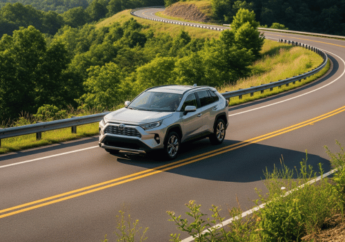 Silver SUV driving on a winding mountain road through green hills
