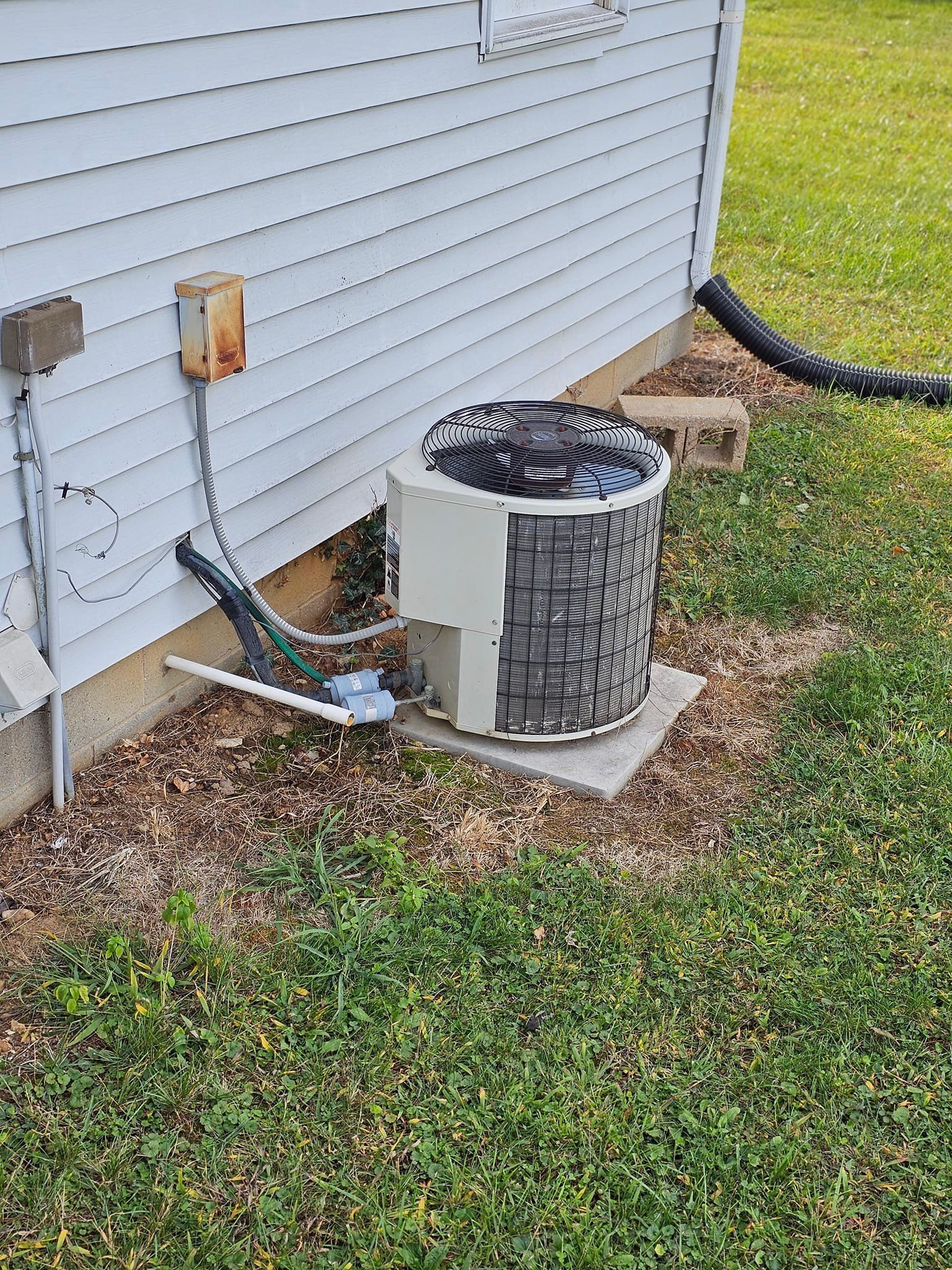 An air conditioner is sitting on the side of a house.
