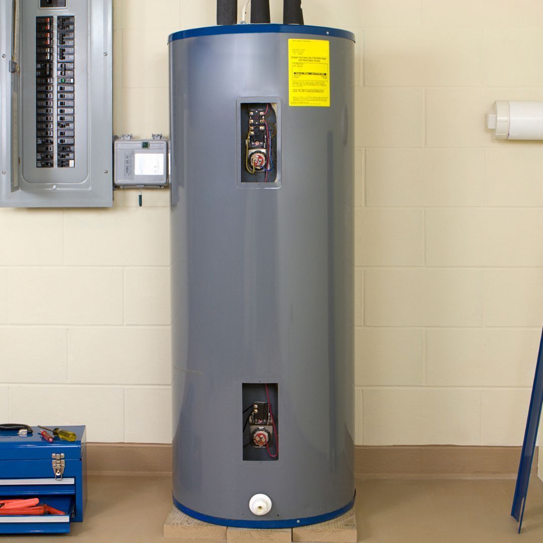 A gray water heater is sitting in a room next to a ladder.