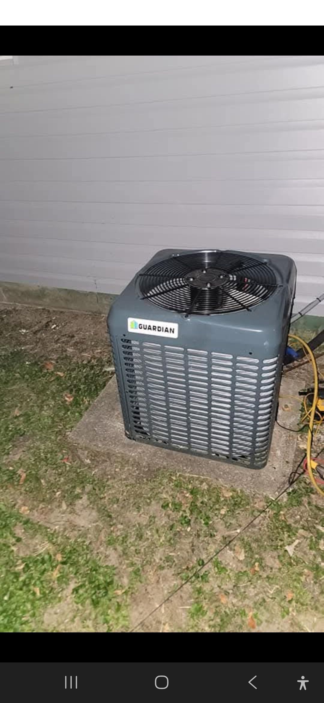 An outdoor air conditioning unit on a concrete pad near a wall.