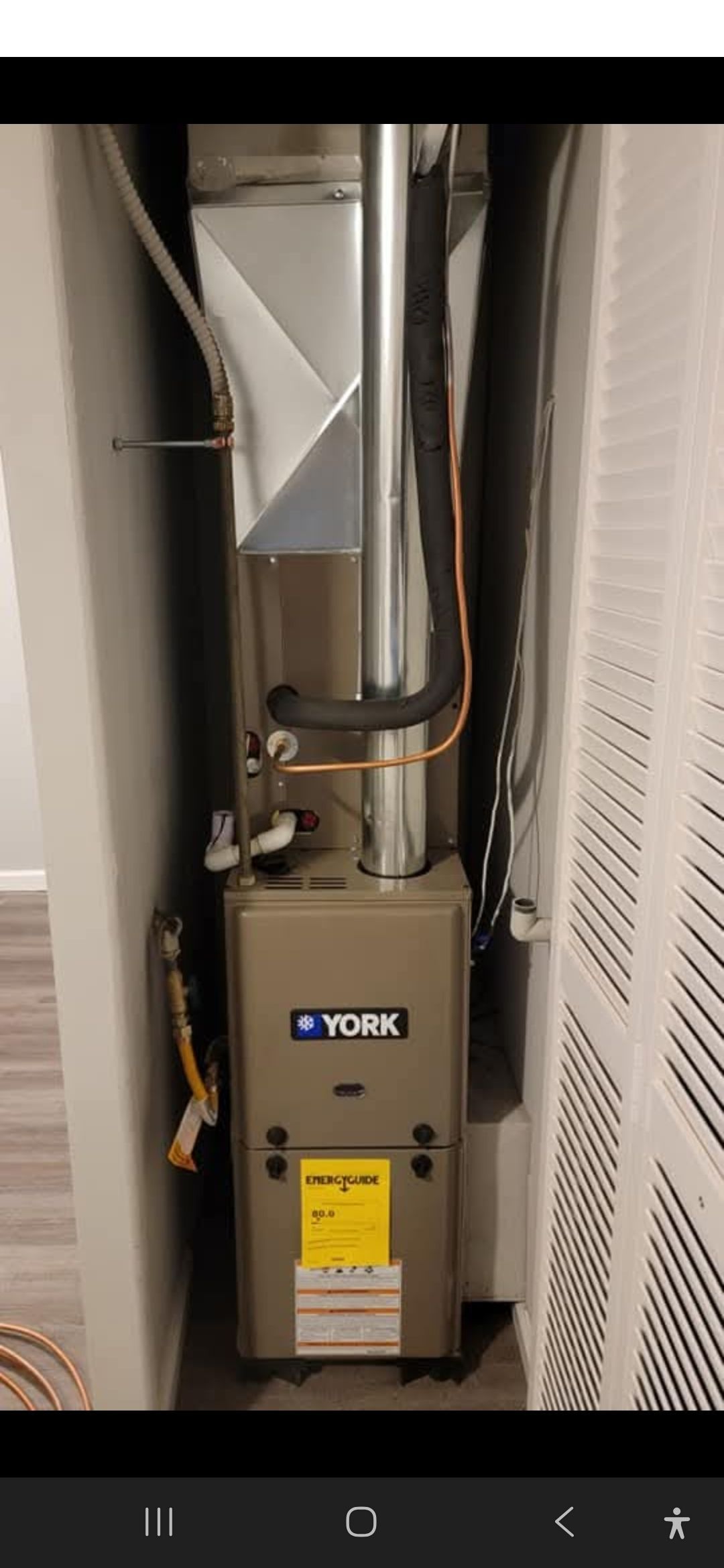 A York brand furnace unit in a utility closet with vent and ductwork.