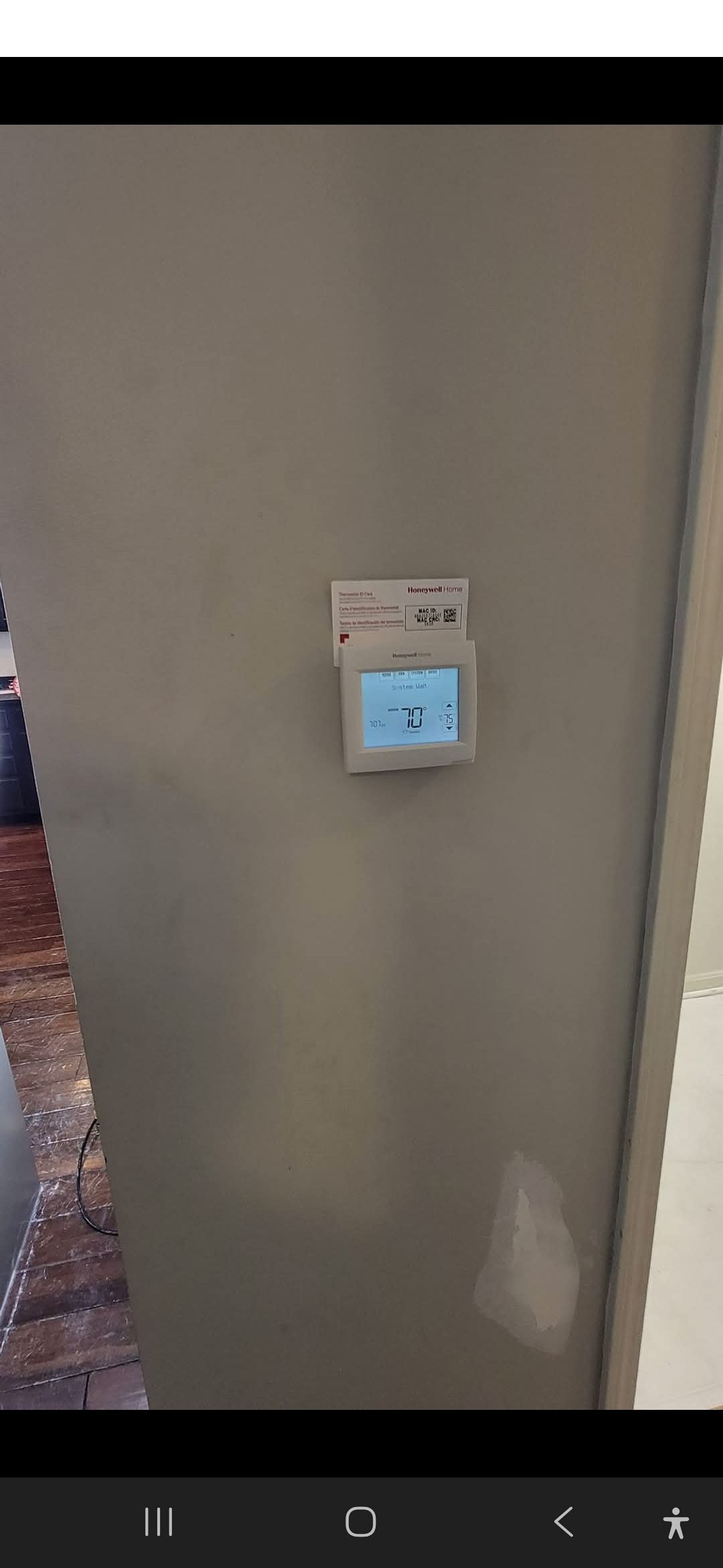 Thermostat on a gray wall, displaying 71 degrees. Small white sign above it.