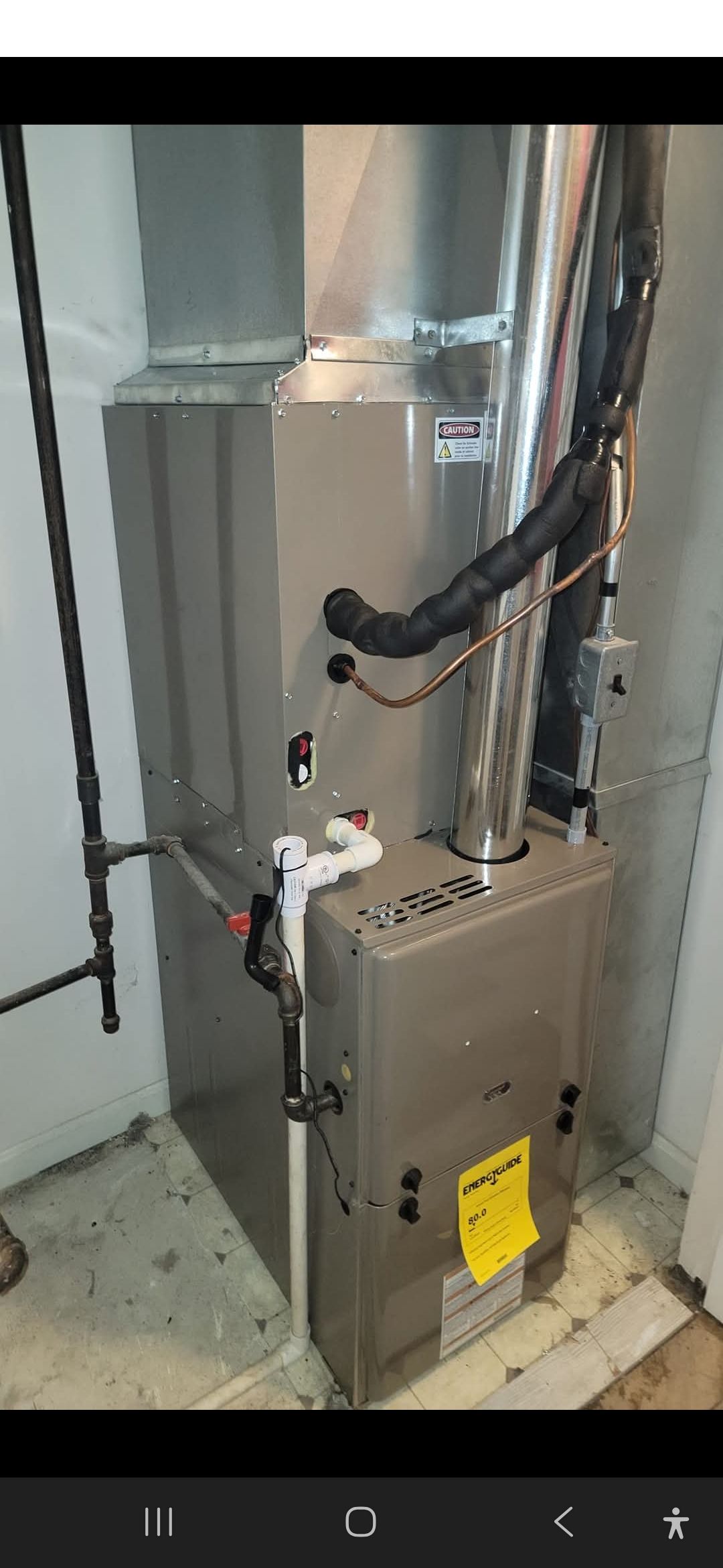 A furnace in a basement setting, with ductwork and piping visible.