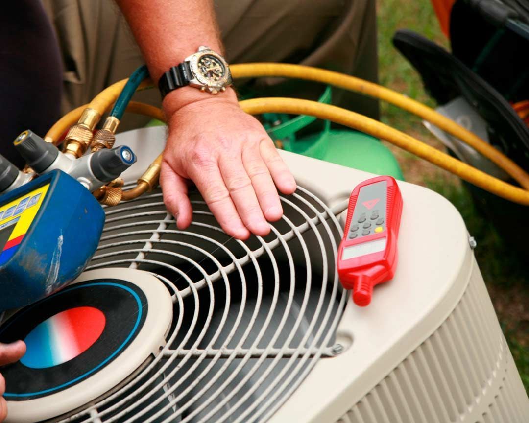 Hand of HVAC technician on air conditioner, with gauges and a red digital reader.