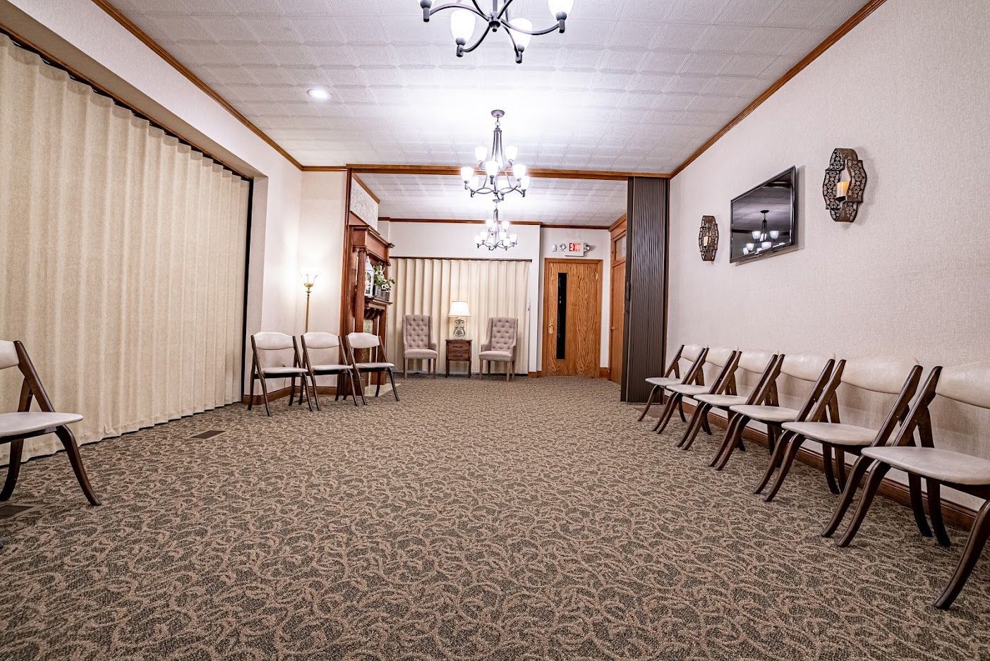 Empty waiting room with rows of chairs, carpeted floor, and ceiling lights