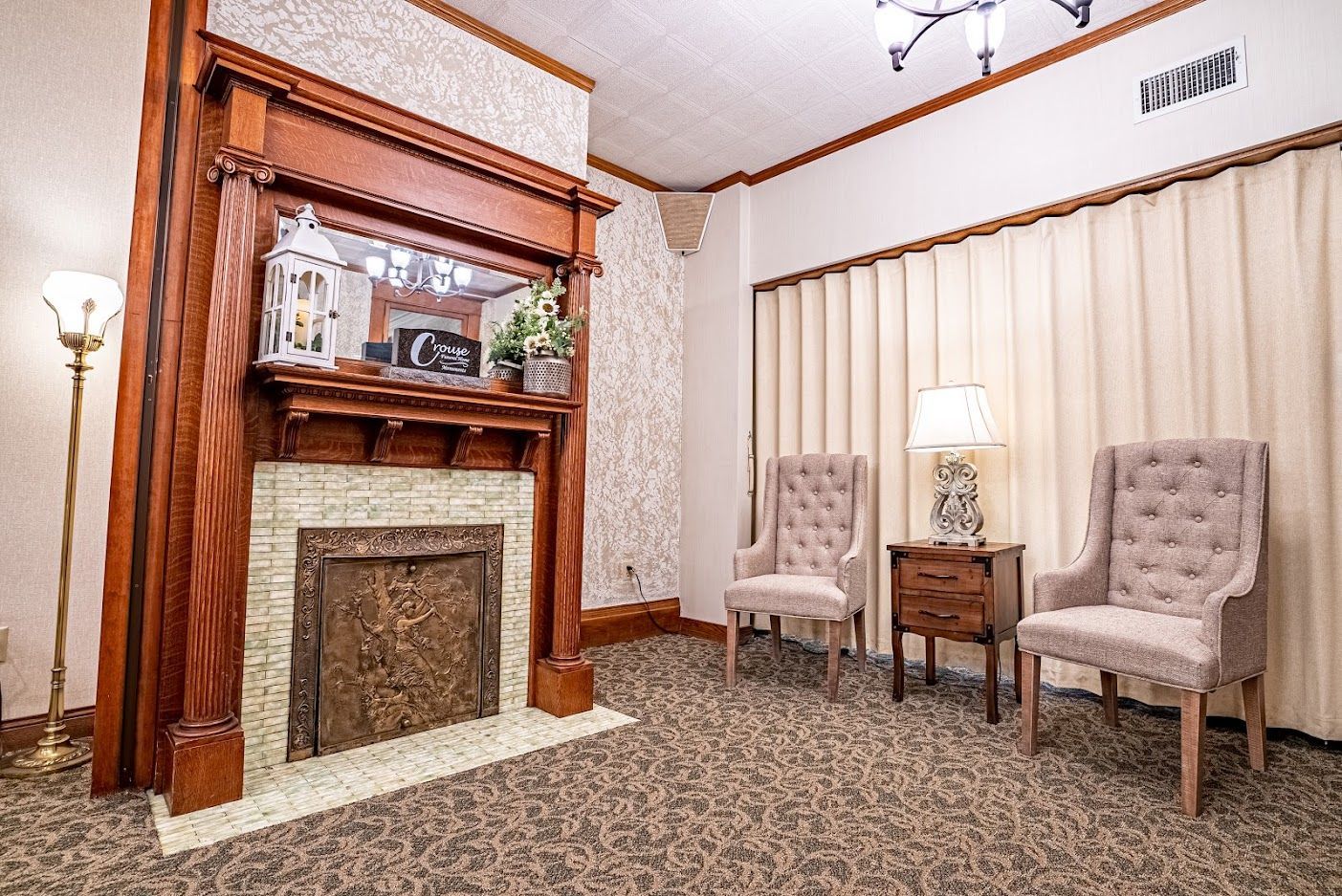 Elegant sitting room with fireplace, two armchairs, lamp, and beige vertical blinds