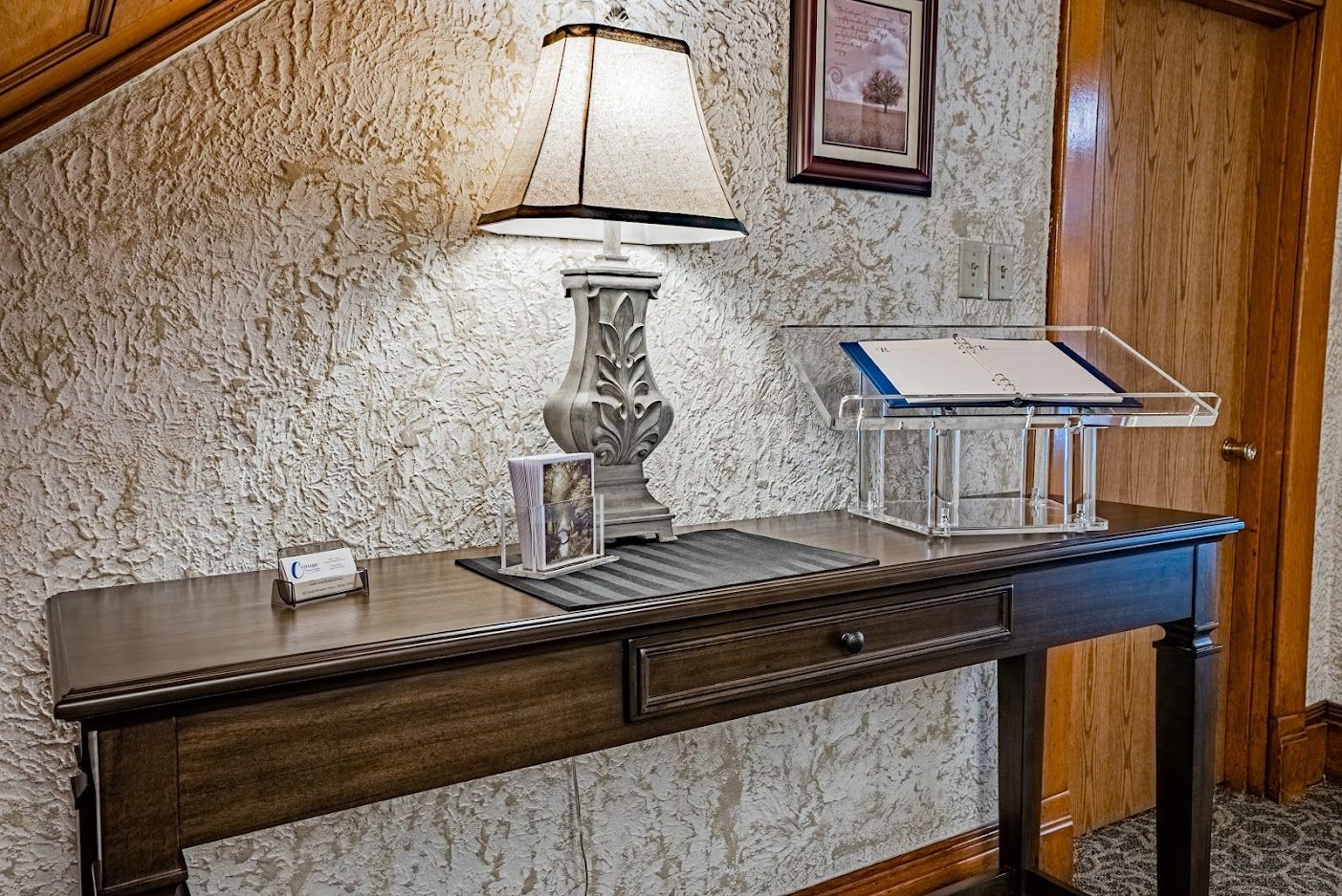 Console table with lamp and framed photo against a textured wall in a hallway