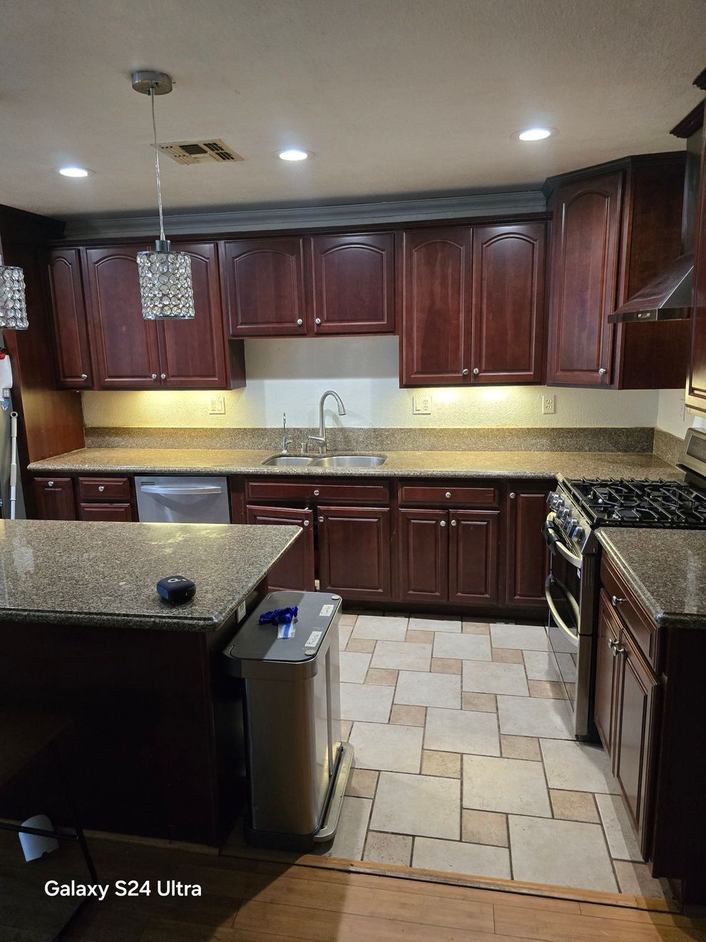 Kitchen with dark wood cabinets, granite countertops, and tiled floor under recessed lighting