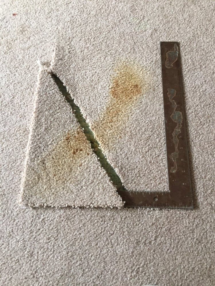 Cracked concrete corner with a rusty metal strip along the right edge