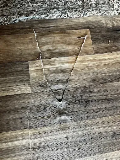 Close-up of a cracked wood surface with a carved V-shaped groove.