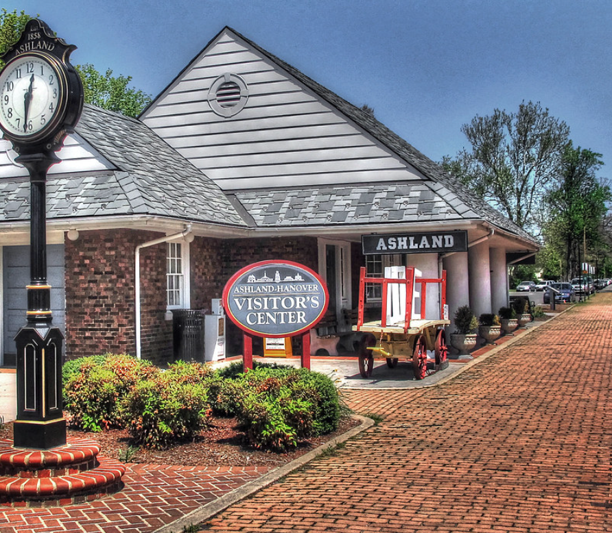 Ashland visitors center with brick walkway, clock, and red wagon cart outside