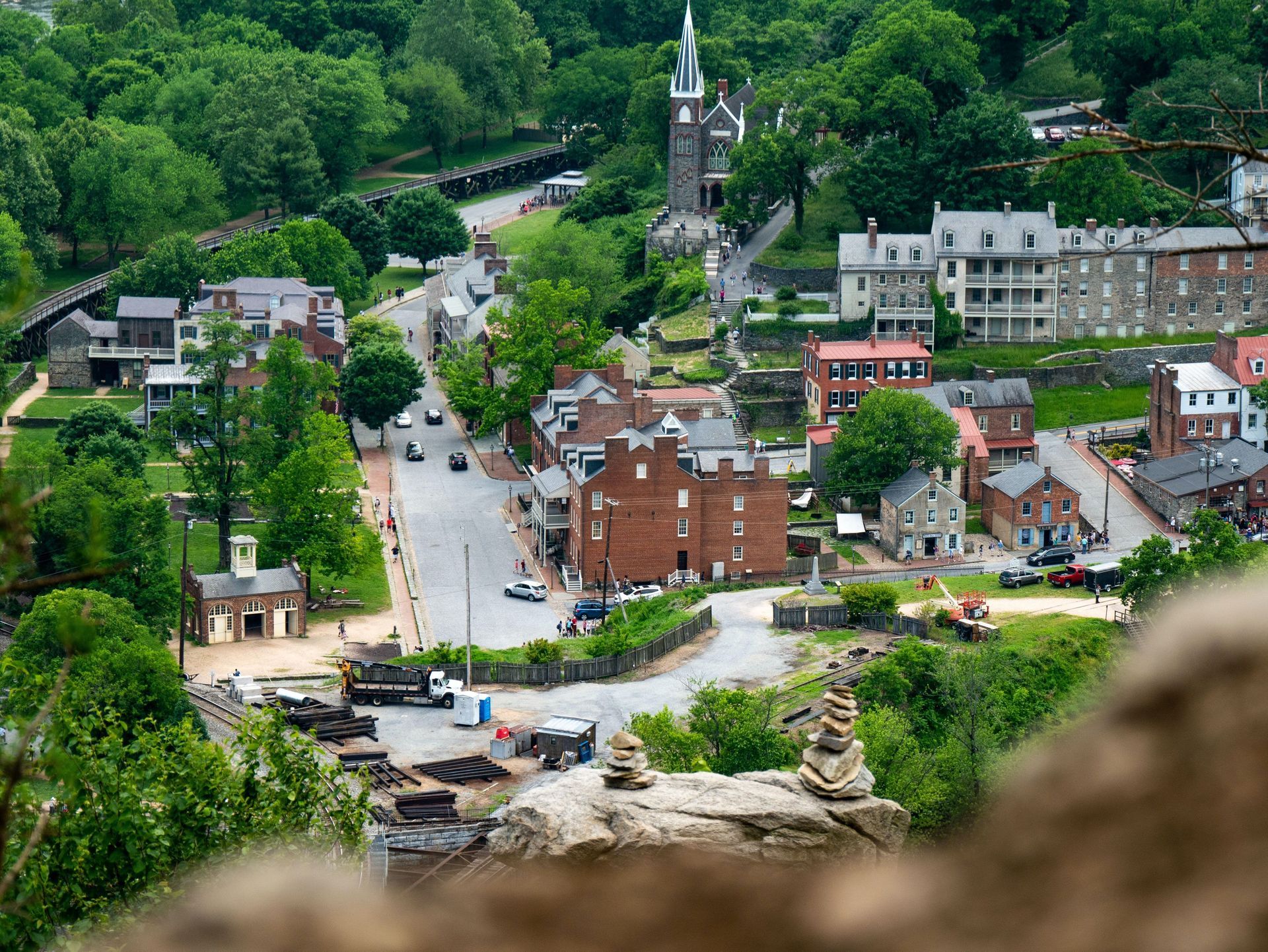 A small town with brick buildings, a church steeple, and a road winding through green hills