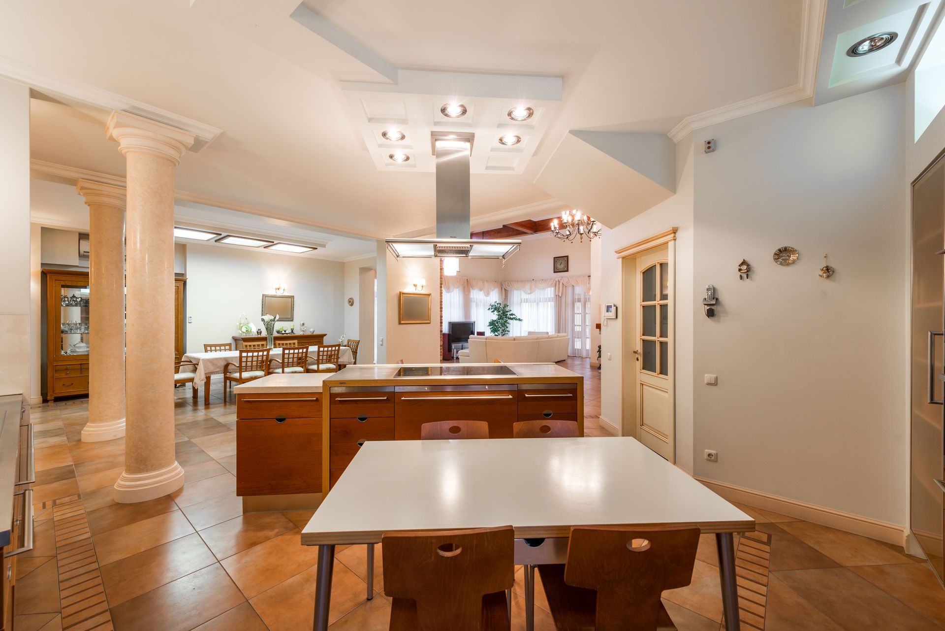 Bright dining room with white walls, wooden furniture, columns, and a table in the foreground