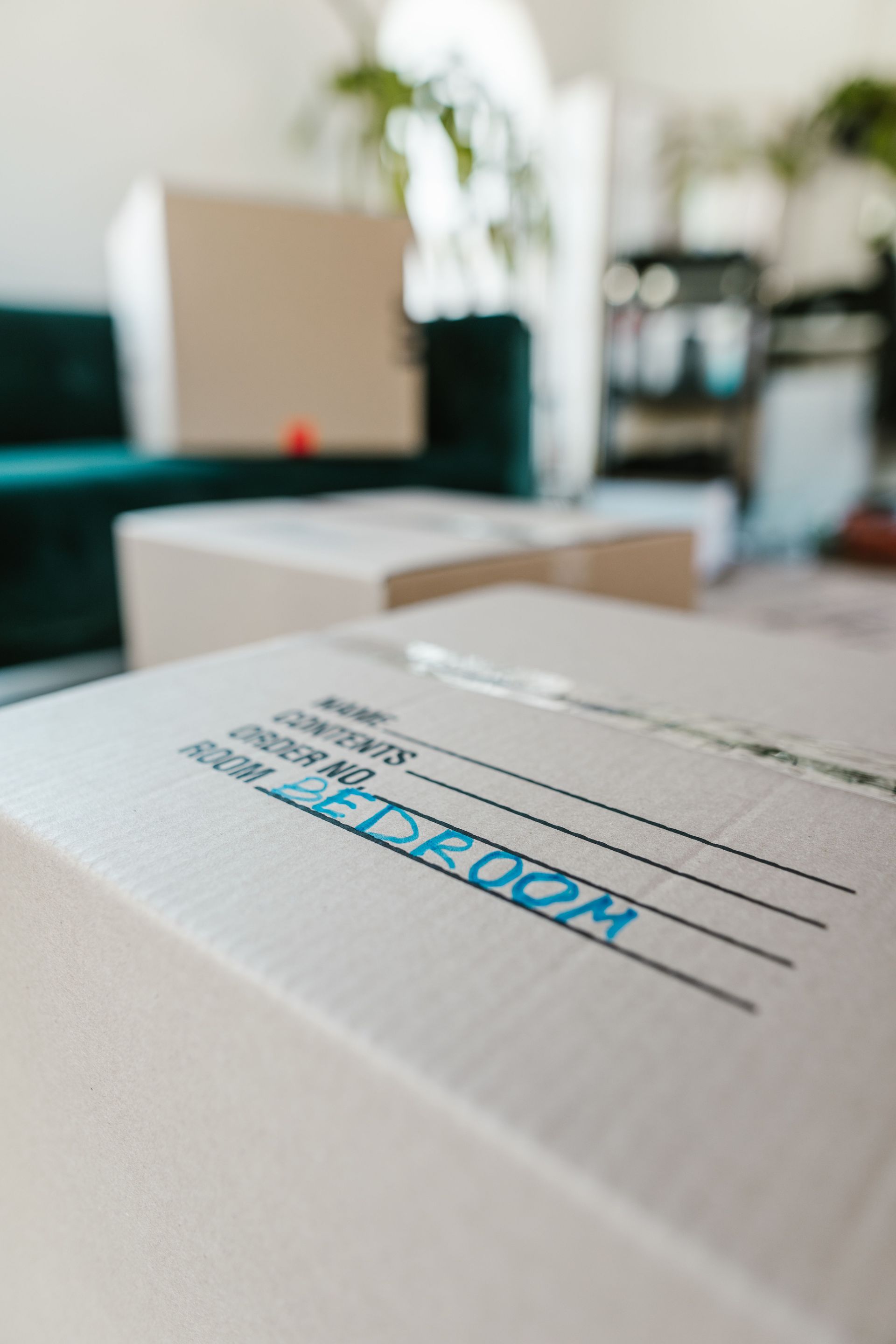 Stacked white cardboard boxes in a blurred office, with one box labeled “ROOM” in blue.