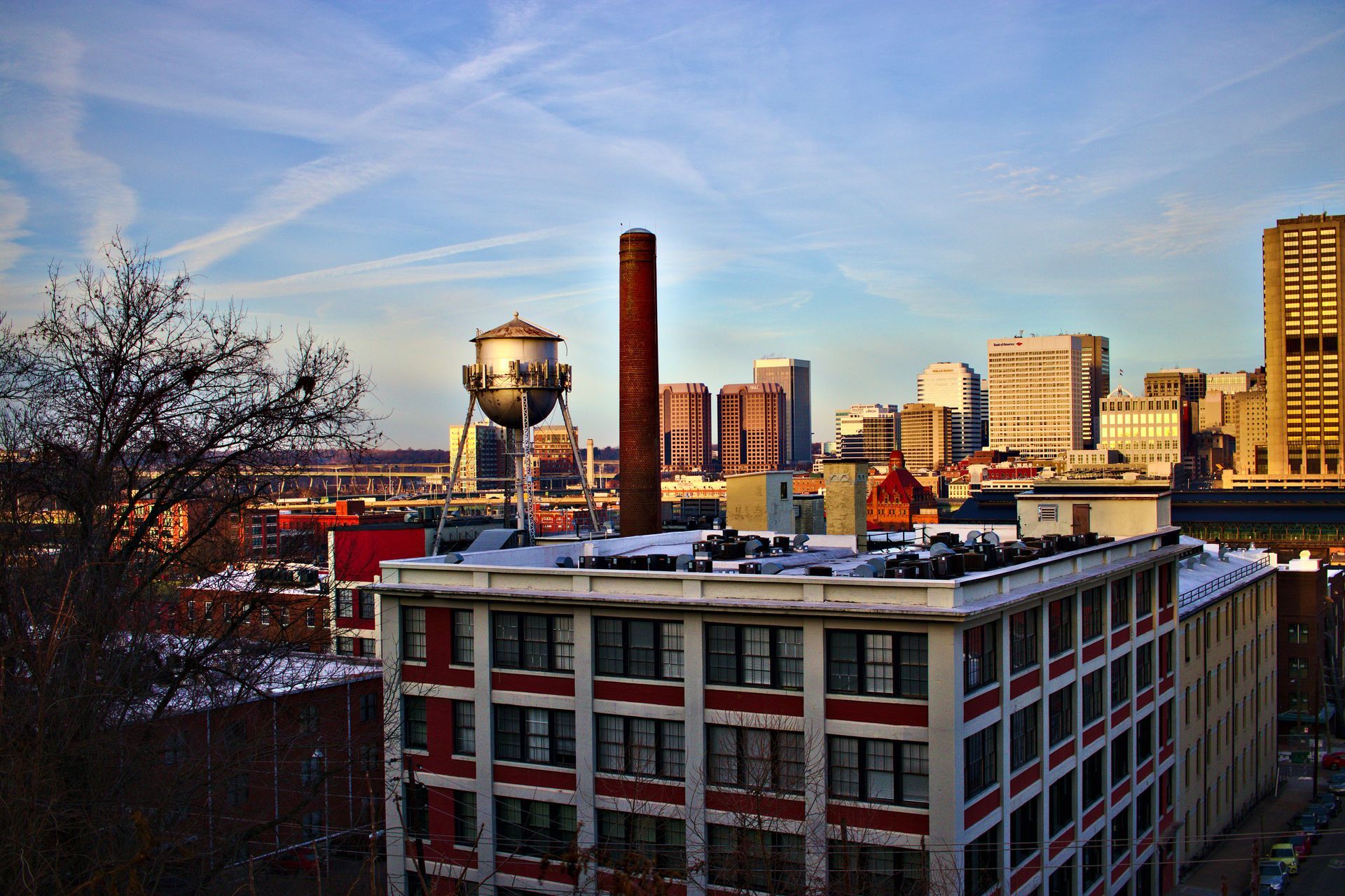 City skyline at sunset with a red-brick building in the foreground and a water tower to the left