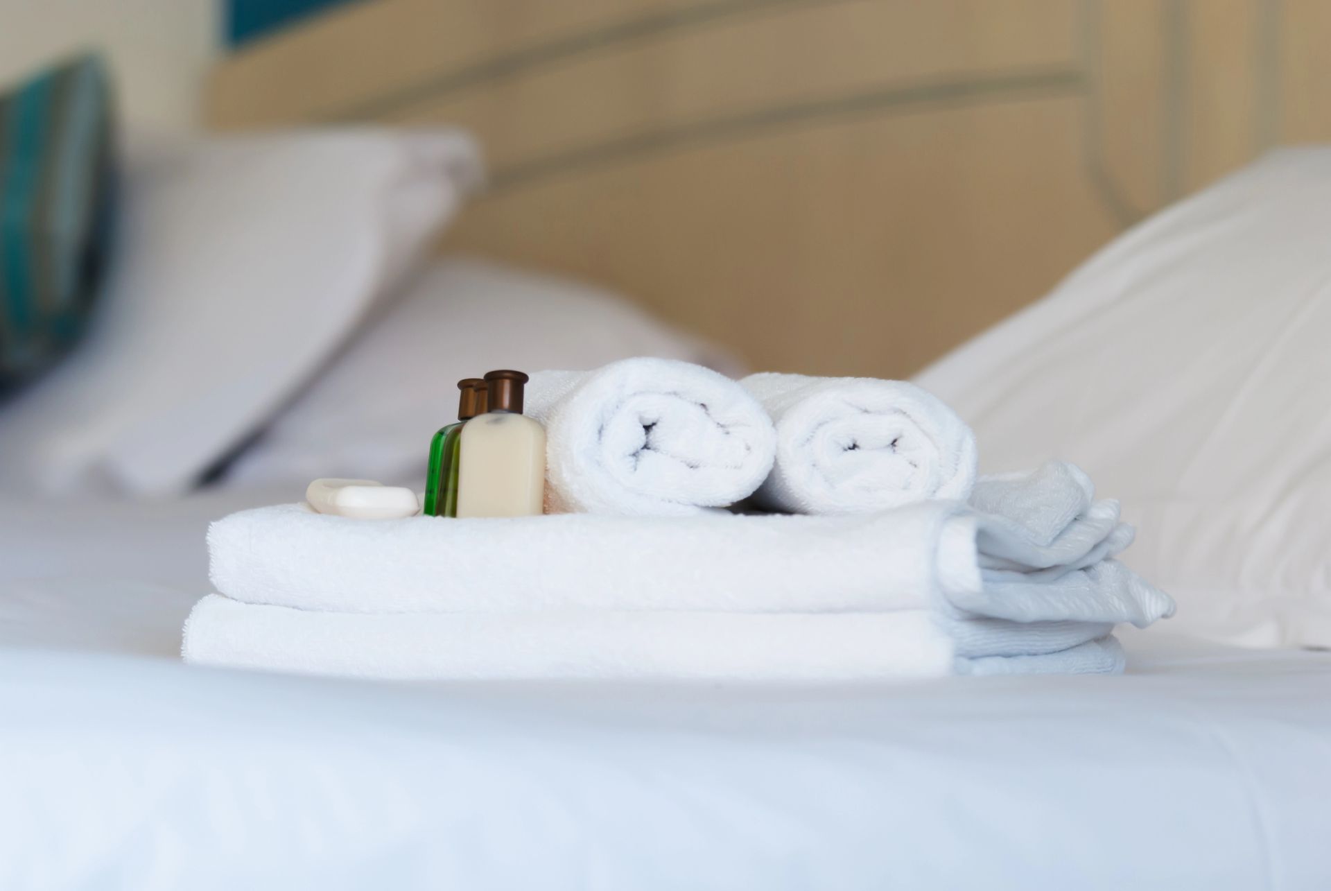 Asciugamani bianchi piegati con cura e articoli da toeletta su un letto in una luminosa camera d'albergo.