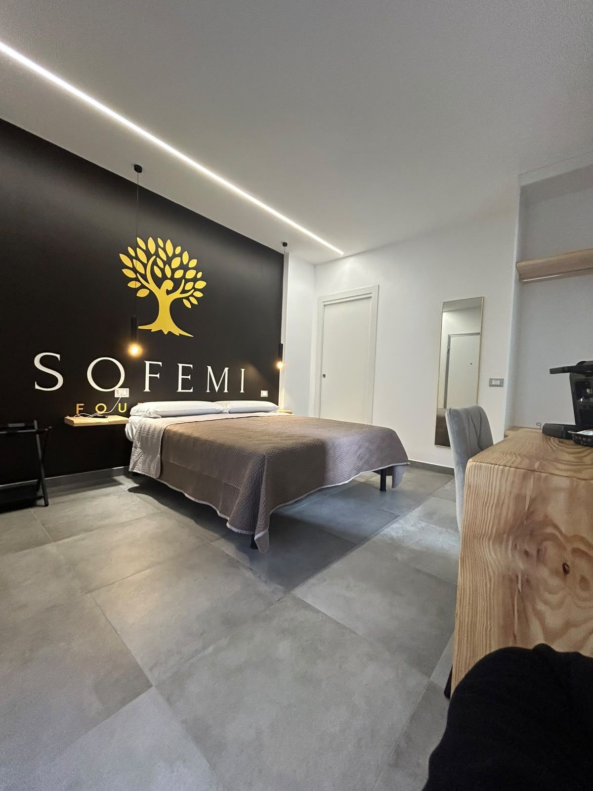 Camera da letto luminosa e con luce soffusa, dotata di un ampio letto, arredi bianchi e porte scorrevoli in vetro che conducono a un balcone.