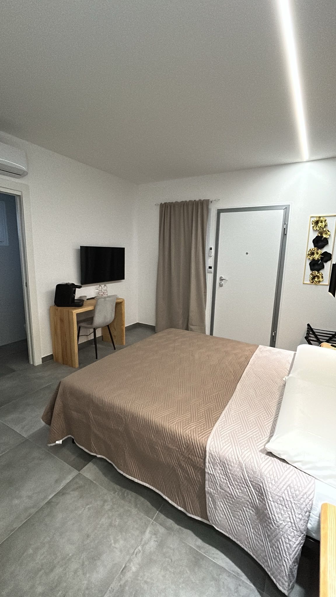 Asciugamani bianchi arrotolati con cura su un letto con un cuscino azzurro e una testiera in legno in una camera d'albergo.