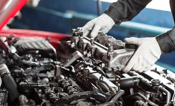 Mechanic working on car engine with gloved hands in a garage
