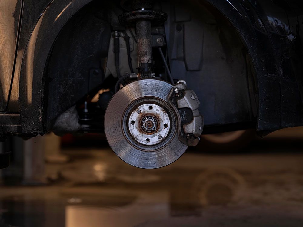 Car brake disc and caliper visible with wheel removed