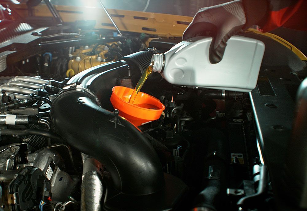 Mechanic pouring engine oil into car engine
