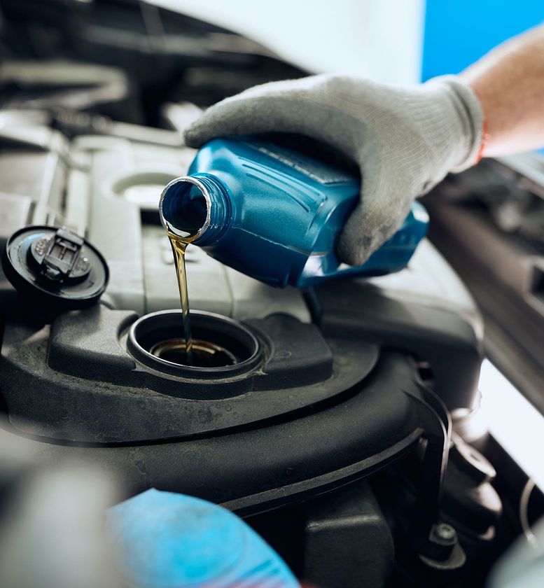 mechanic pours motor oil