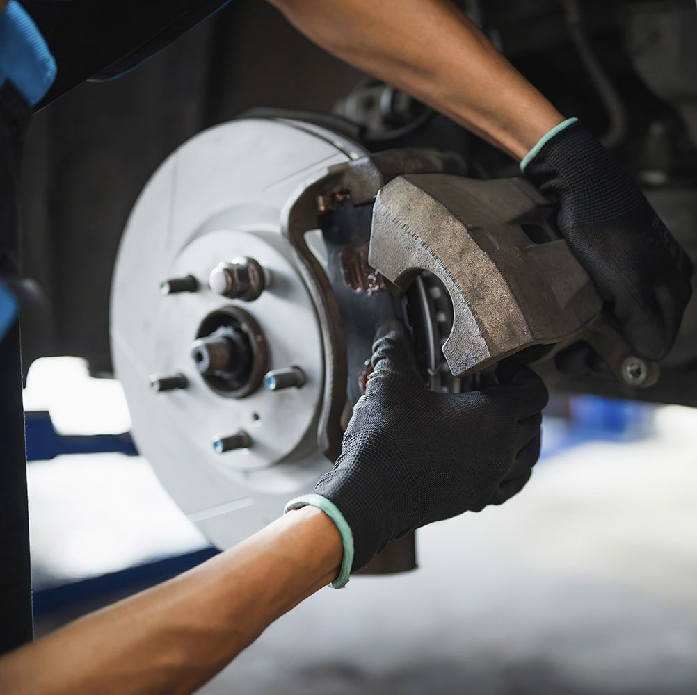 Auto mechanic installing car front brake caliper