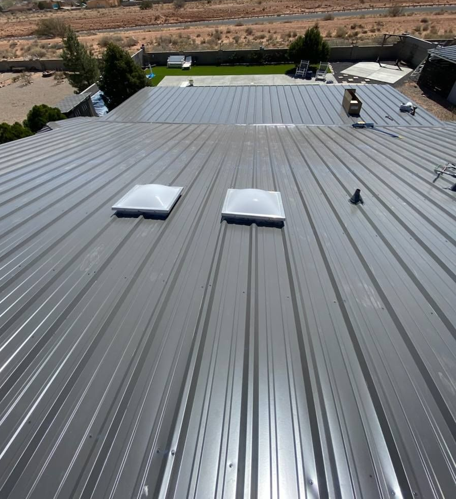 Gray metal roof with two skylights. Outdoors, sunny.