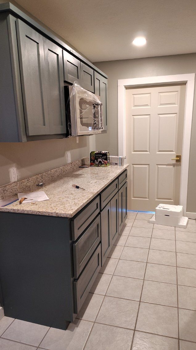 Kitchen remodel with gray cabinets, beige countertops, and a built-in microwave.