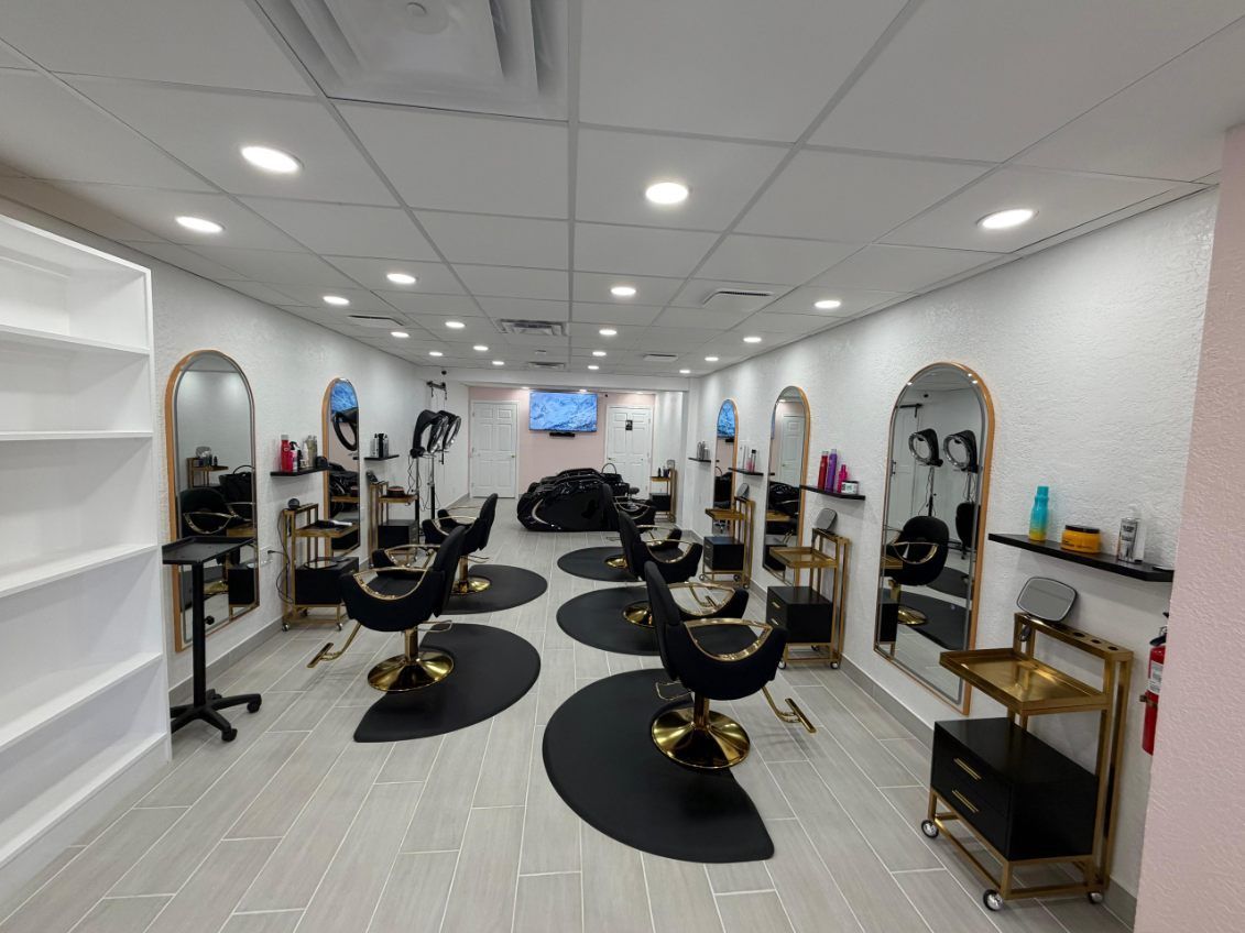 Hair salon interior with black and gold styling stations, mirrors, and chairs.