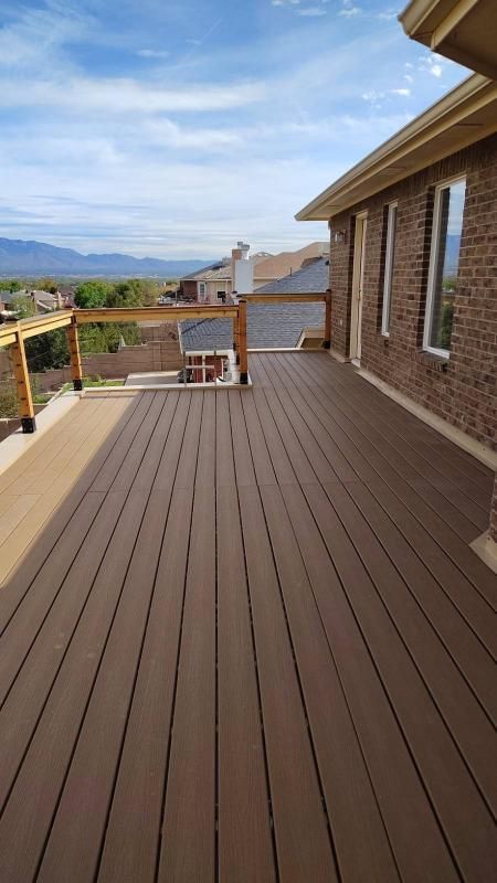 Composite deck with brown boards, attached to a brick house. View of mountains in the background.