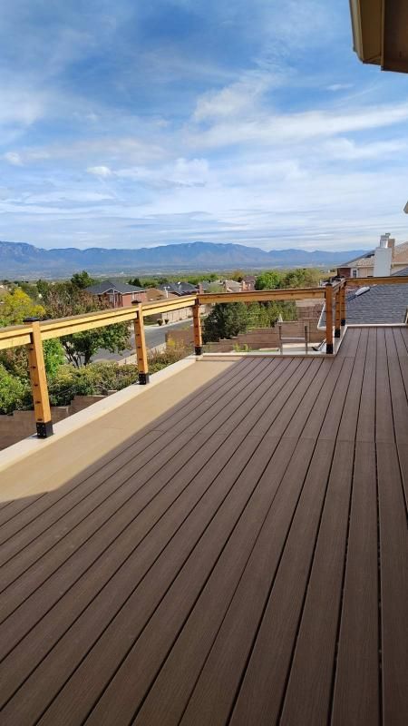 Wooden deck overlooking a valley and mountains under a blue sky.