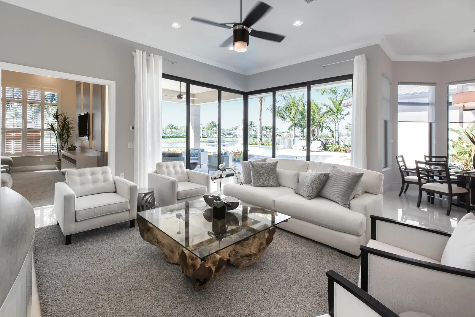 Living room with white furniture, gray walls, and large windows overlooking water.