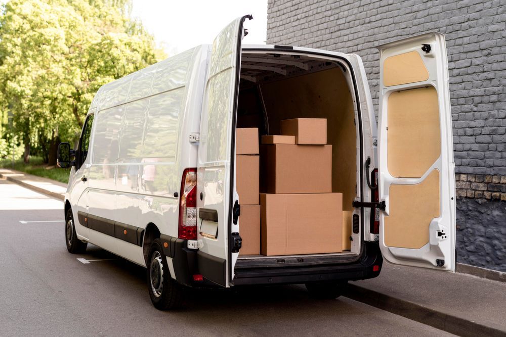 White Delivery Van With Open Back Doors Filled With Cardboard Boxes on a Street — J & V Express Couriers In Marian, QLD