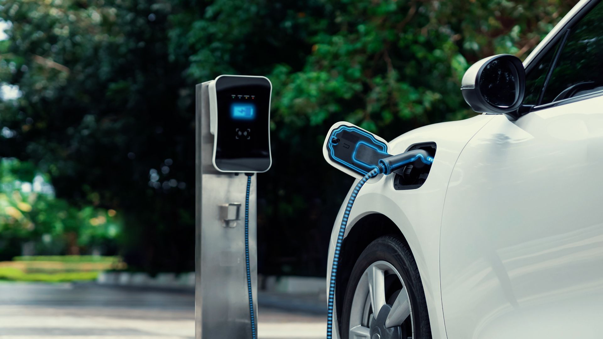 Electric car charging at a station outdoors, with the charging plug connected to a white vehicle.