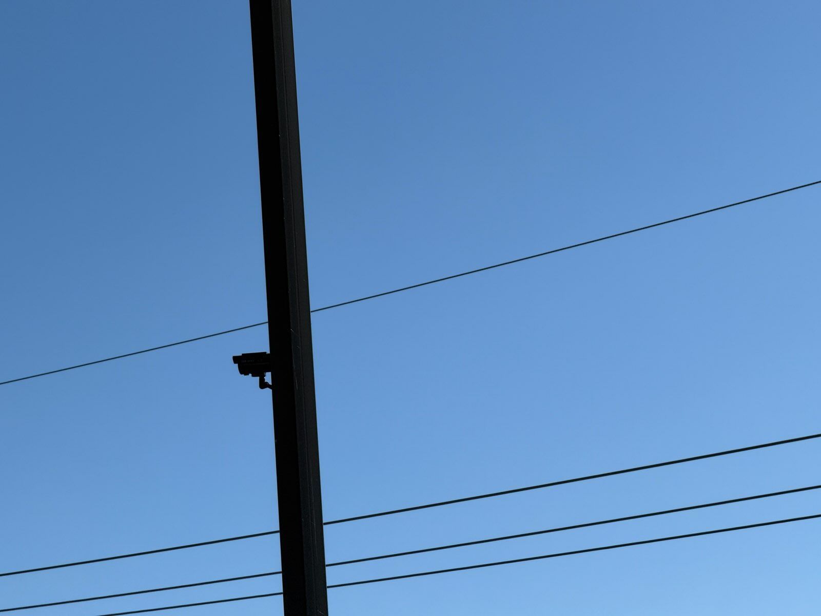 Utility pole against a blue sky with power lines crossing the frame