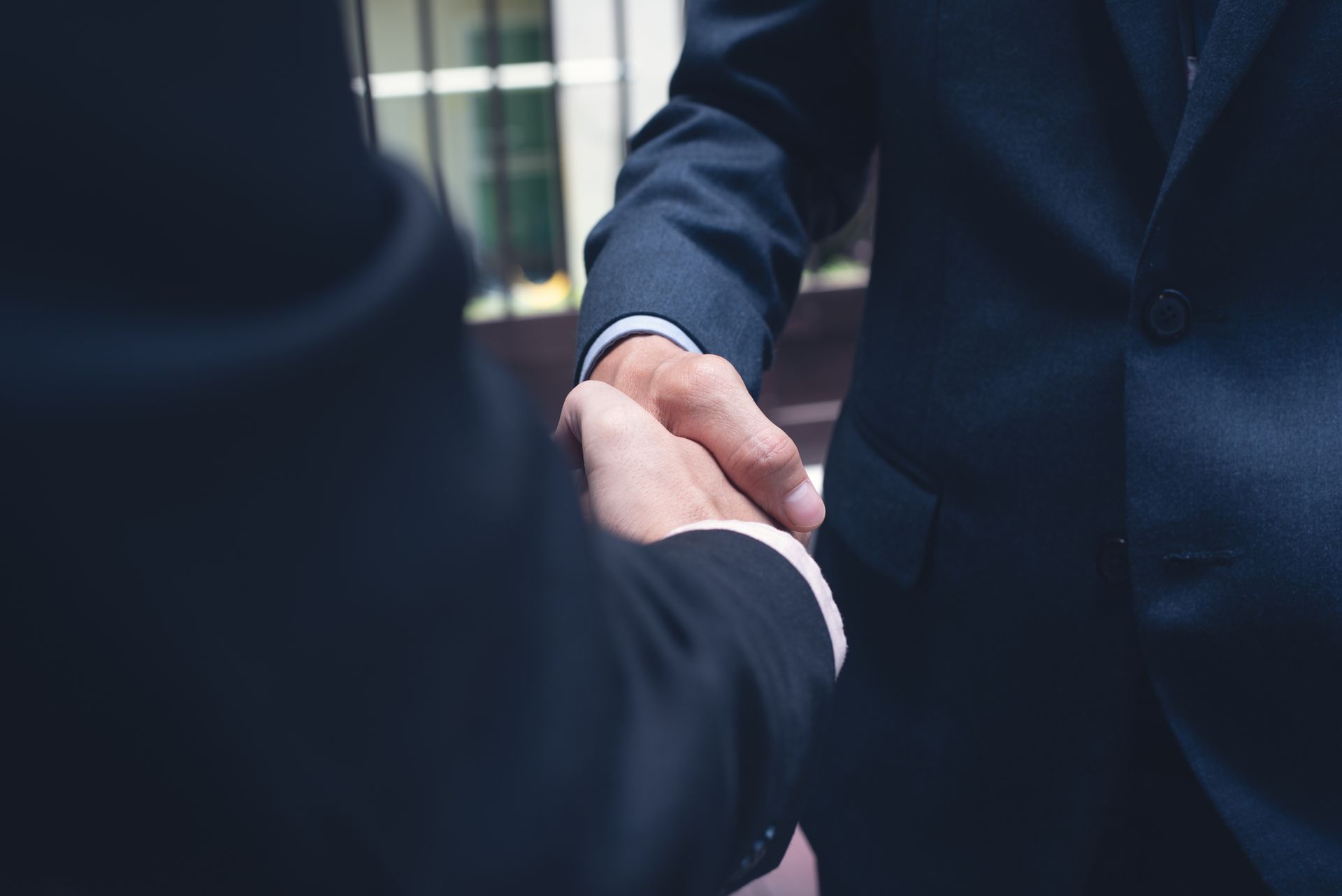 Two men in suits are shaking hands in front of a building. Two men in suits are shaking hands in front of a building.