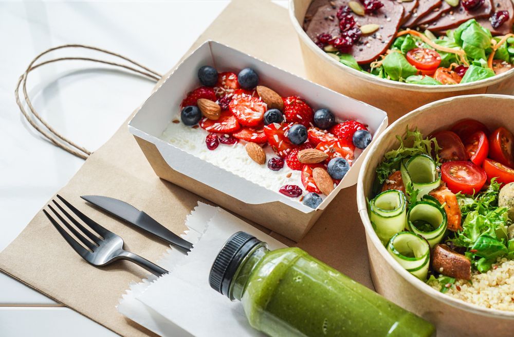 A table topped with bowls of food and a bottle of green juice.