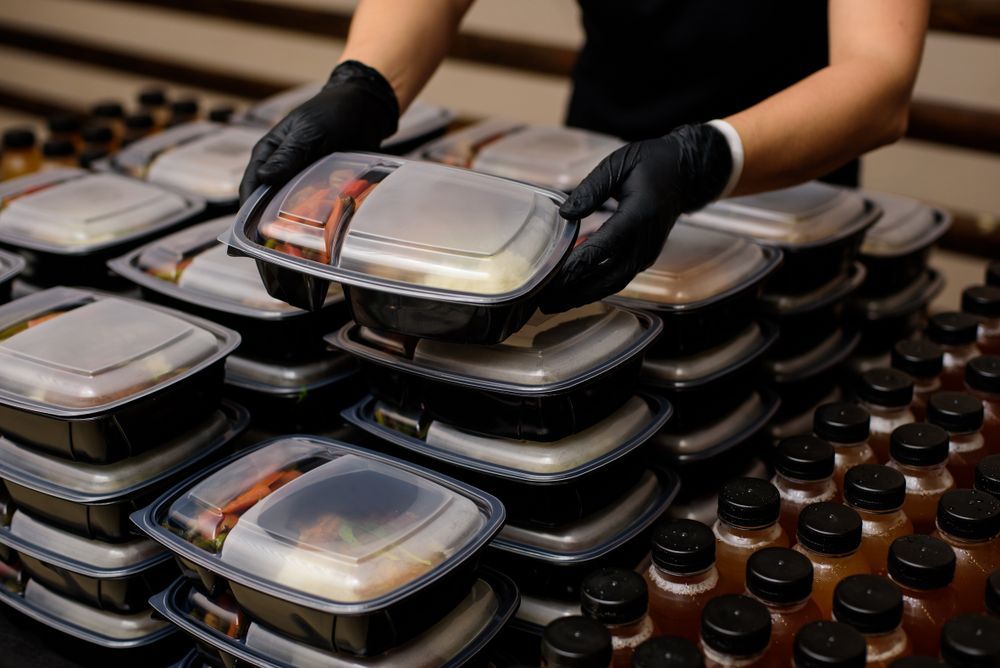 A person is stacking plastic containers of food on top of each other.