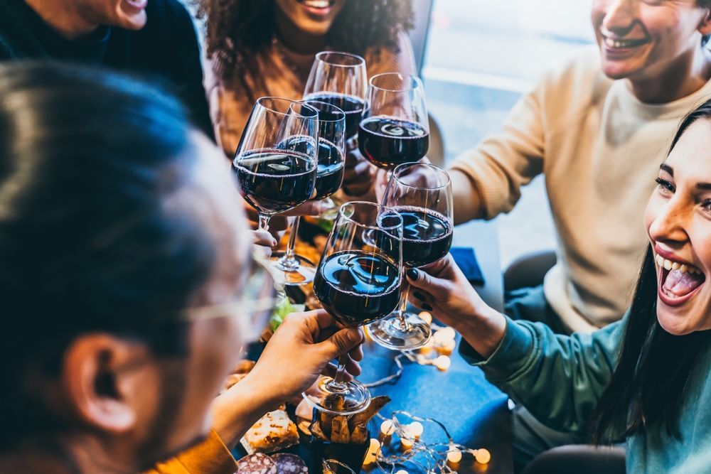 A group of people are sitting at a table toasting with wine glasses.