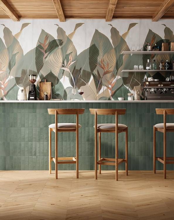 Un bar con tre sgabelli e una parete verde con foglie.