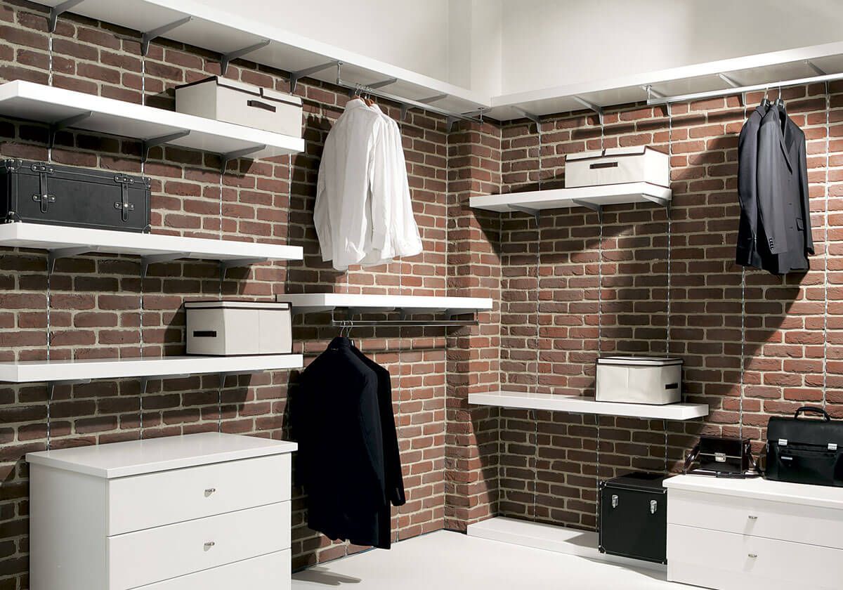 Una cabina armadio con una parete in mattoni e mensole bianche