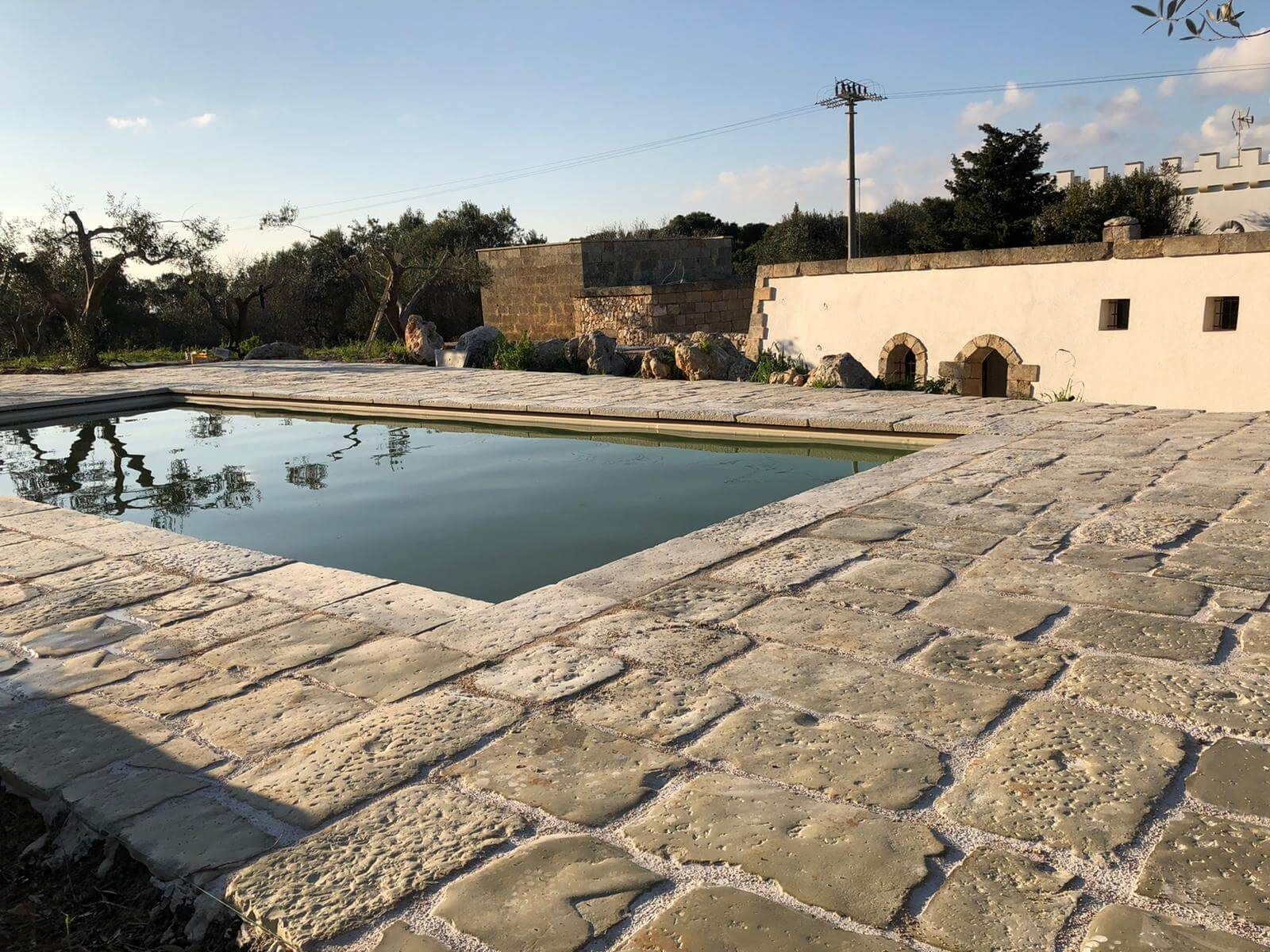 Una grande piscina è circondata da mattoni e alberi.