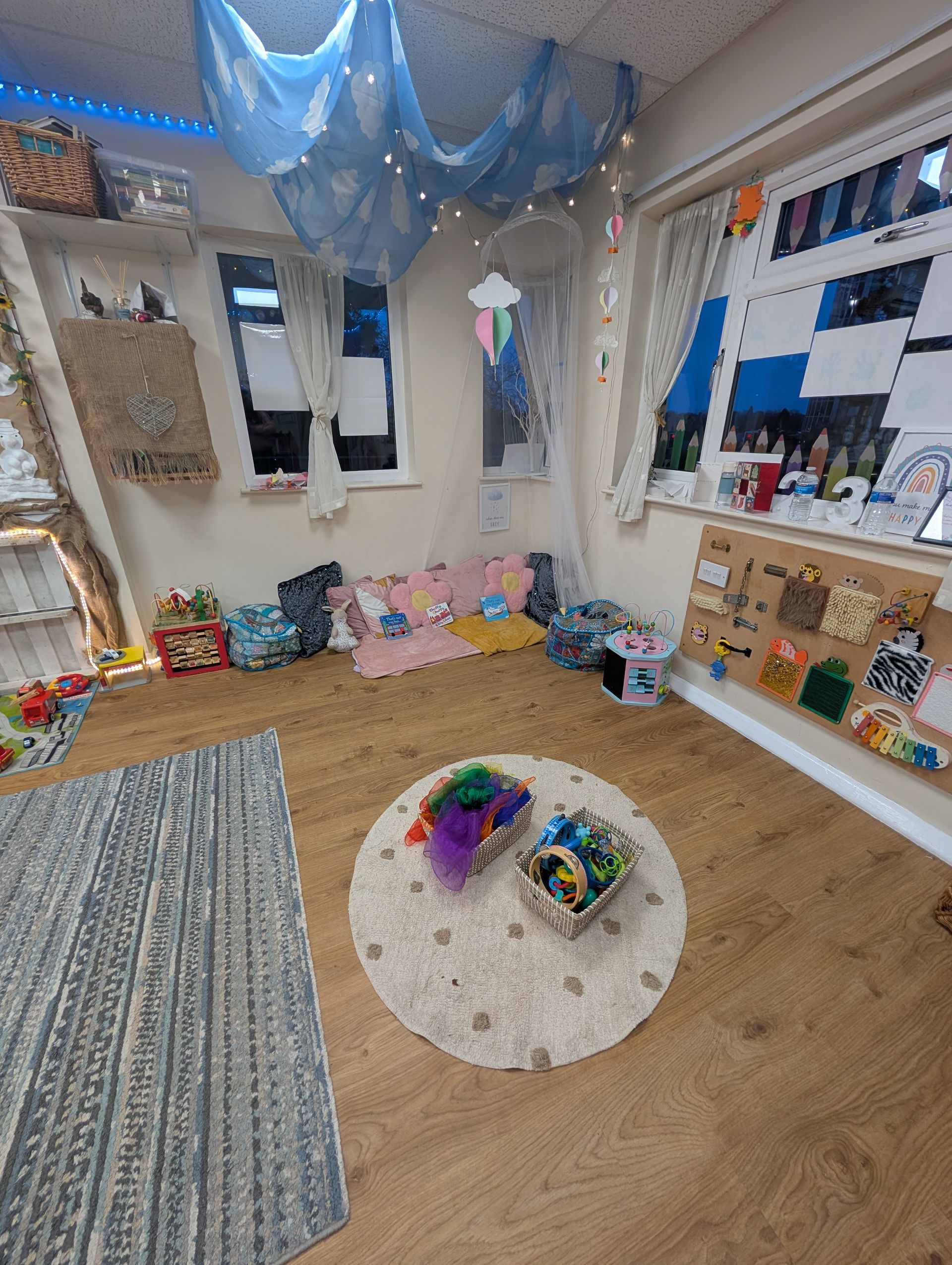 Bright playroom with rugs, toys, wall mirrors, and a blue ceiling canopy