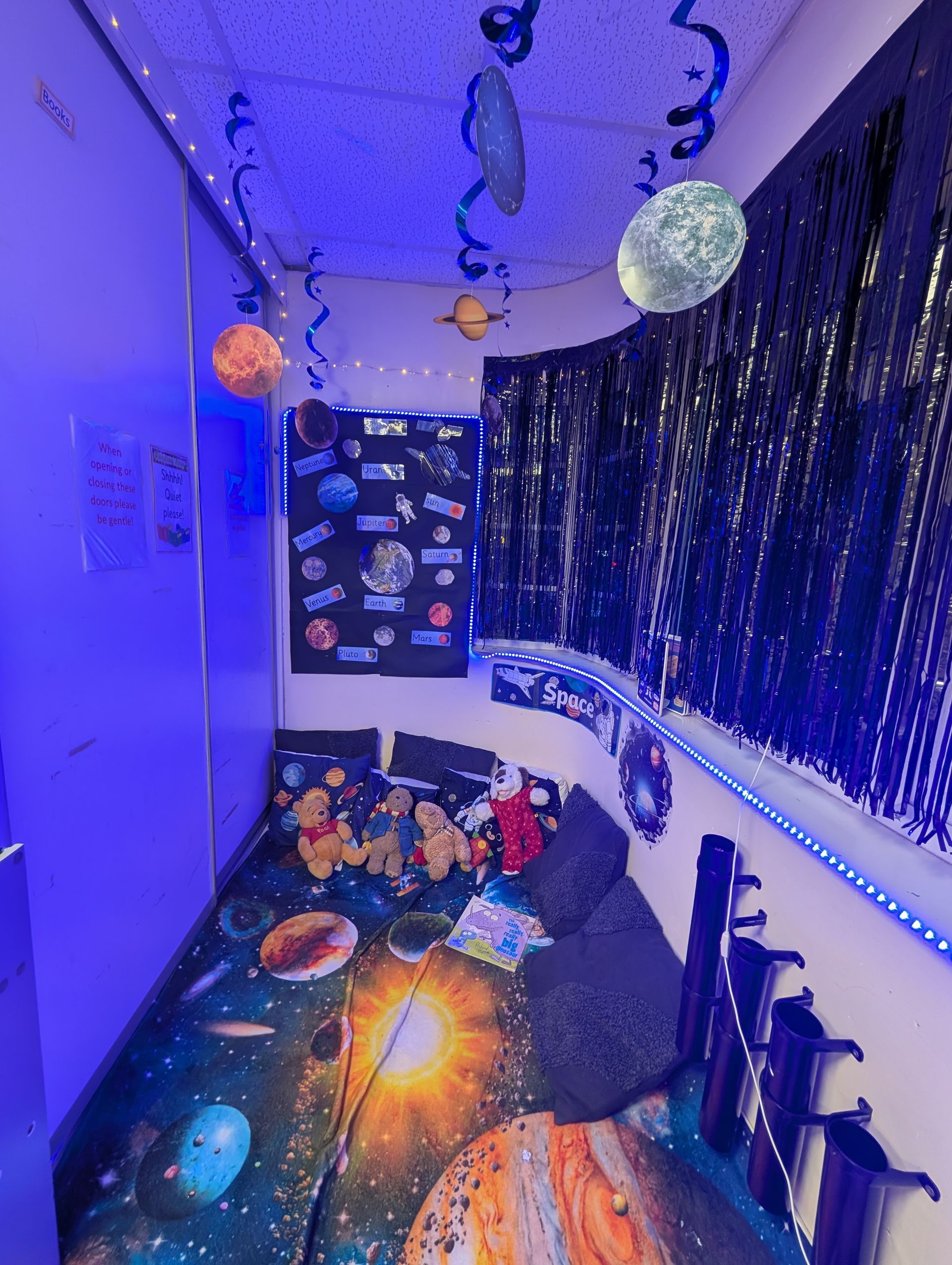 Blue-lit bedroom with Halloween decorations, hanging paper bats, and spooky wall and ceiling decor