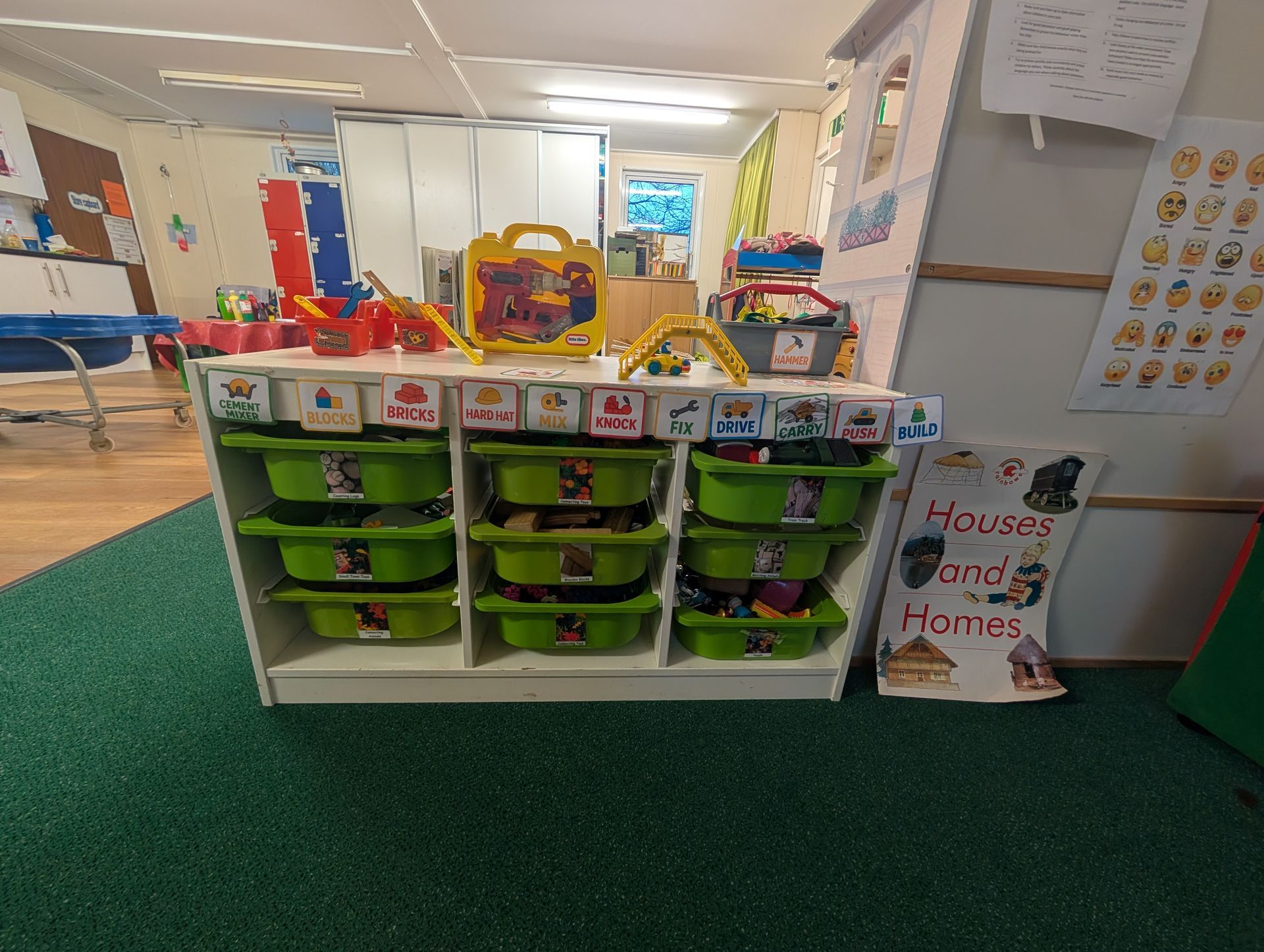 Classroom storage cubbies with green bins and colorful toys in a play area