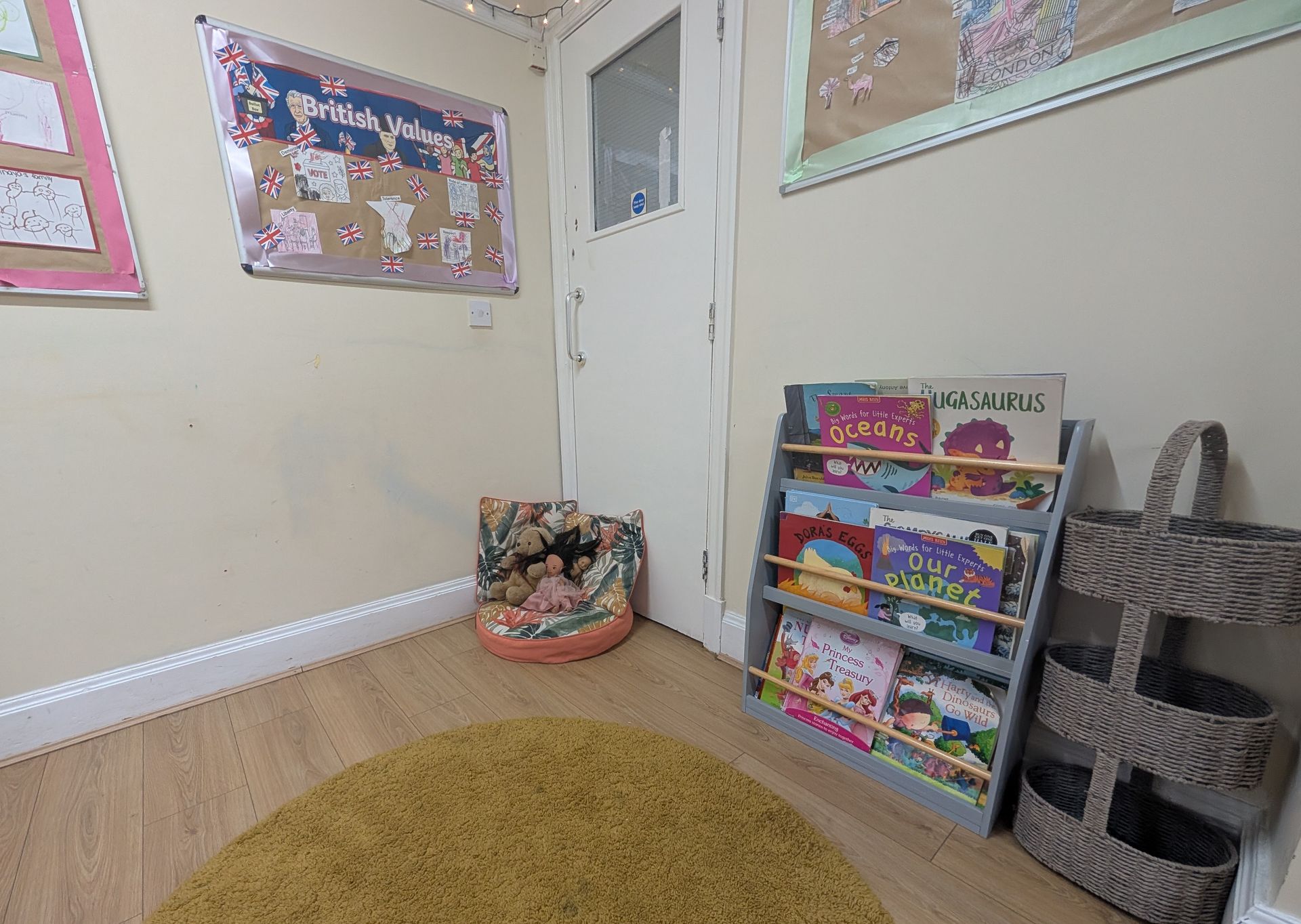 Empty child’s room with a white door, toy organizer, wall posters, and a round rug.