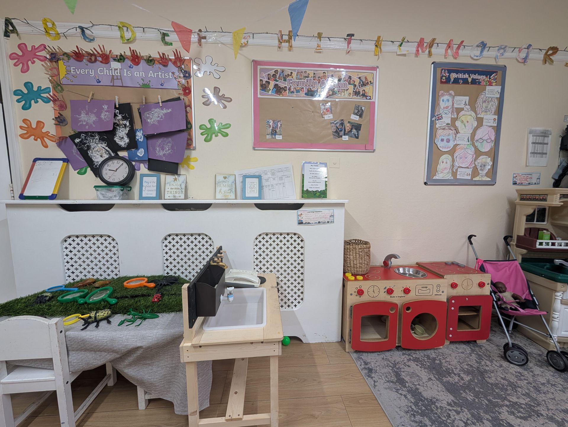 Classroom corner with desks, bulletin boards, posters, and colorful play items against a beige wall